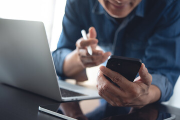 Businessman making face time video calling, using online meeting app via mobile app on smart phone with laptop computer and digital tablet on office table
