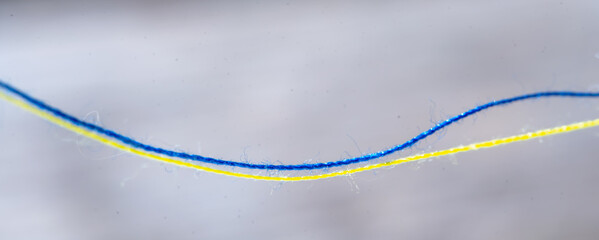 Yellow and blue threads as a symbol of the struggle of the Ukrainian people against russian aggression for their freedom and democracy. Horizontal image