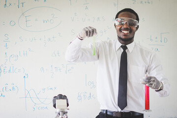 African science teacher conducting experiment mixing liquids in flask, laboratory assistant in goggles showing chemical reaction in lesson, chemistry science concept