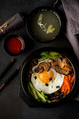 Korean dish bibimbap with broth on a dark background. View from above