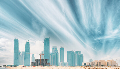 Obraz premium Construction crane is involved in development of new multi-storey residential building. View of modern skyscrapers in Dubai. Construction development of residential houses among modern glass