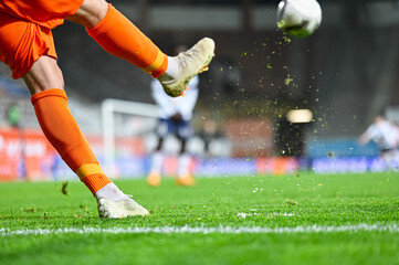 Football player's legs and blades of grass flying after kicking the ball during soccer match. - obrazy, fototapety, plakaty