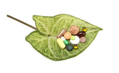 Vitamins, pills, green leaf and tablets on light copy space background.