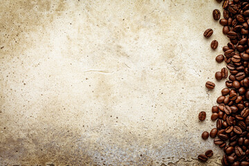 Grunge light stone background with coffee beans. Scratched concrete table texture with roasted grains