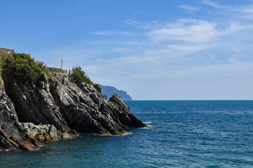 Fototapeta na wymiar Seascape from the bay of Nervi with the Anita Garibaldi Promenade on top of the cliff and the promontory of Portofino in the background, Genoa, Liguria, Italy