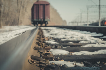 Close-up of old railway nails to attach rails to wooden sleepers. Blurred freight wagon stands on the spare track of the railway. Selective focus