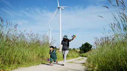 Mother and his son run around with windmills in a wind turbine field, mother teaching his son how to live in harmony with nature and technology, family relationships.