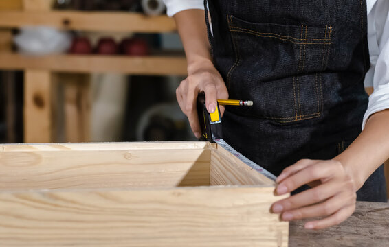 carpenter use measuring tape working on a wooden project in carpentry workshop
