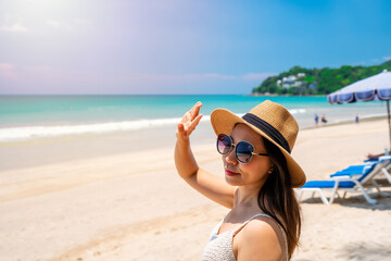 Young woman traveler wearing sunglasses covering face by hand to protect UV rays from the sun at...