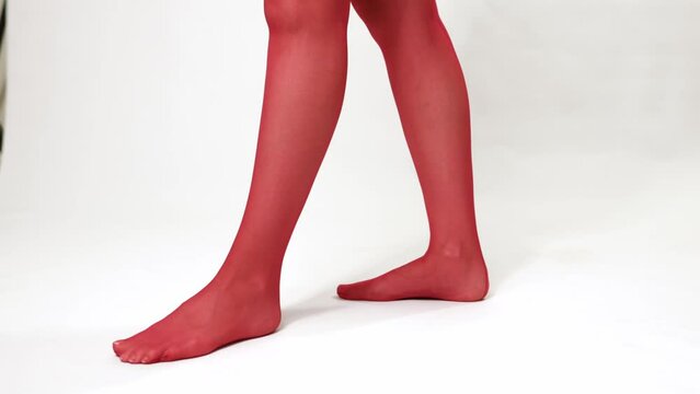 Woman puts on a classic red stocking with a mesh on her beautiful legs - close-up 4k video