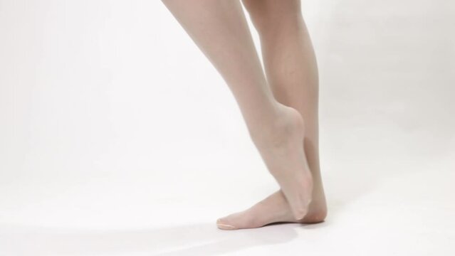 Woman puts on a classic white stocking with a mesh on her beautiful legs - close-up 4k video