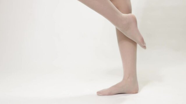 Woman puts on a classic white stocking with a mesh on her beautiful legs - close-up 4k video