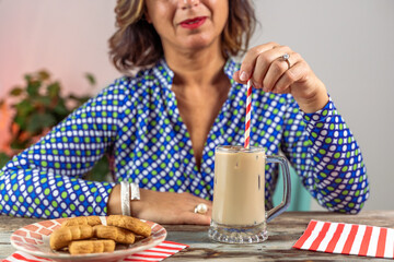 woman dressed in blue shirt sitting drinking cold coffee through a straw