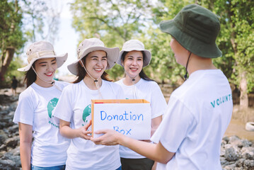 Group of asian diverse people volunteer holding a donation box for fundraiser to emergency situation such as help ukraine, flood victims, food for children, charity event.Volunteering conceptual.