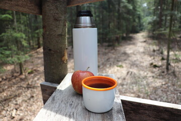 Termos z herbatą i jabłko. Odpoczynek w lesie - obrazy, fototapety, plakaty