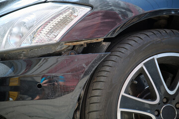 Dented car with damaged fender parked on city street side. Road safety and vehicle insurance concept