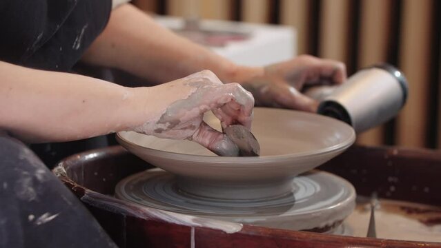 Heating the clay plate on the pottery wheel using a hairdryer and removes excess clay from the inside