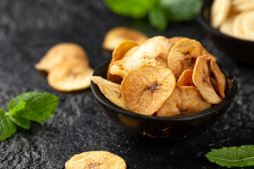 Dried banana chips, snack in rustic coconut bowl