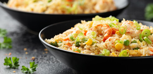 Prawn fried rice with eggs and vegetables in black bowl. Healthy asian food.