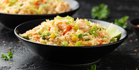 Prawn fried rice with eggs and vegetables in black bowl. Healthy asian food.