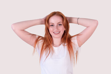 Fototapeta premium smiling redhead young woman with tousled hair stretches on a light background