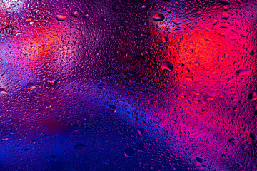 Drops of condensate on the sweaty glass. Cold foggy glass on background night lights