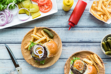 Cheeseburger sliders with fries and a platter of toppings.