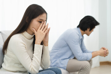 Family problems, Asian women cover her face and sit separately from husband feel disappointed after quarrels at home.