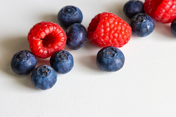 Raspberries and blueberries on a white table