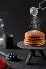 Saupoudrer avec du sucre en poudre de la pile de crêpes. Pancakes sur une présentoir à gâteaux...
