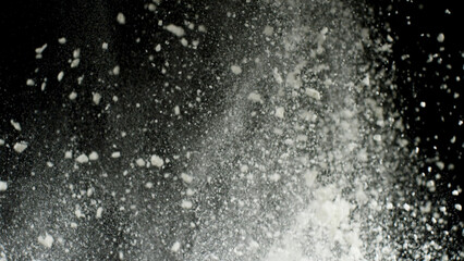 Obraz na płótnie Canvas White dry powder explosion with white dust falling down isolated on black background. Stock footage. Close up for white dry paints being tossed up, monochrome.