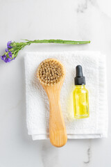Obraz na płótnie Canvas Natural bristles exfoliating brush for dry face or body massage on marble background. transparent bottle with skin care products. Detoxing skin ritual. mockup