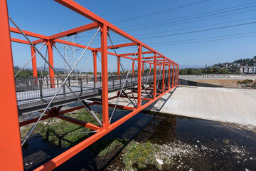 Fototapeta premium View of the new Taylor Yard bike path bridge spanning the Los Angeles River between Elysian Valley - Frogtown and the Glassell Park and Cypress Park neighborhoods in Los Angeles, California.