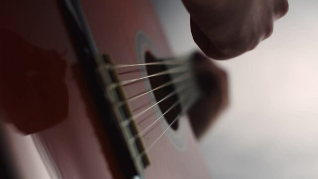 Male musician plays guitar strings using pick, closeup of hands. Male musician plays guitar strings with pick. Man play musical instrument