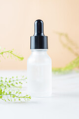 White transparent cosmetic bottle and pipette with drop of oil serum liquid essence on beige background, cosmetics laboratory, dropper and hygiene.