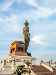 Phutthamonthon Buddha walking statue at public Buddhist park in Nakornpathom province under evening cloudy sky in Thailand