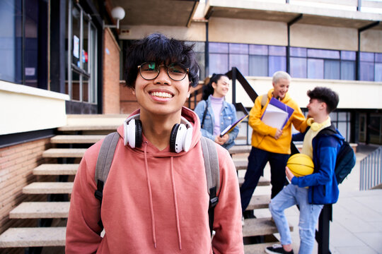 Close Up Shot Of Cheerful Happy Asian Teenage Guy Looking At Camera Smiling. Funny Portrait Of A Young Male Student Boy At Campus University. Man Laughing At High School.