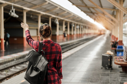 Young Asian woman backpacker traveler walking alone at train station platform with backpack. Asian woman waiting train at train station for travel. Summer holiday traveling or young tourist concept