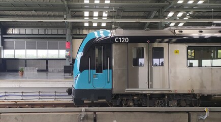 South indian kochi metro public passenger electric train front side with closed door arriving and passing through aluva metro station platform terminal background with copy space. Closeup side view.