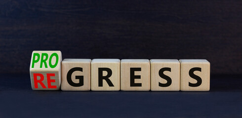 Regress or progress symbol. Turned wooden cubes and changed the word Regress to Progress. Beautiful black table black background. Business regress or progress concept. Copy space.