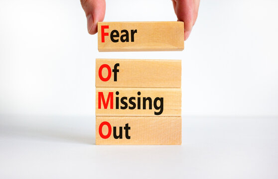 FOMO fear of missing out symbol. Concept words FOMO fear of missing out on wooden blocks on a beautiful white background. Businessman hand. Business FOMO fear of missing out concept. Copy space.