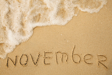 Fototapeta premium November - handwritten on the soft beach sand.