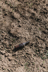 Environmental pollution, empty bottle lying on the bare ground 
