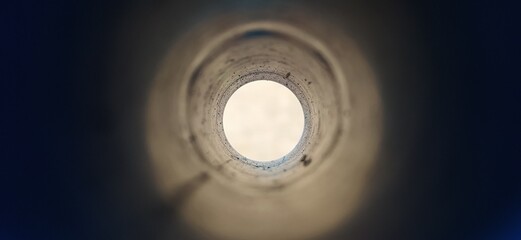 Close-up deep endless round large and long concrete pipe hole with blurry black foreground and...