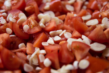 Pomidory pokrojone w kostkę wymieszane z czosnkiem w plasterkach - obrazy, fototapety, plakaty