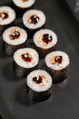 Simple maki with shrimp on a plate on black stone background.
