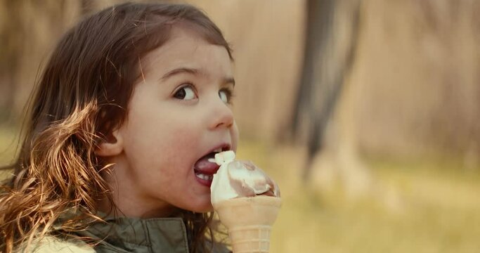 Cute toddler girl enjoying an ice cream cone. Spring, summer exterior shot.