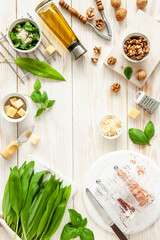 Ingredients for Wild Garlic Pesto cooking, delicious savory sauce for Italian pasta  -  Ramson herbs, cheese, walnuts, basil, olive oil. Top view on white background