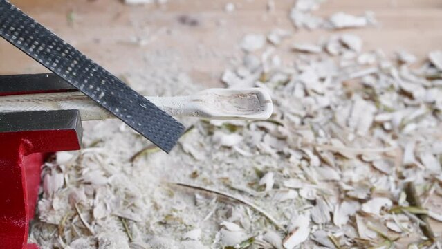 Footage of a wooden spoon carving with wood rasp on a workbench with wood chips, Germany