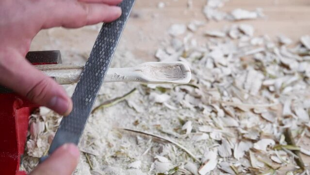 Footage of a wooden spoon carving with wood rasp on a workbench with wood chips, Germany